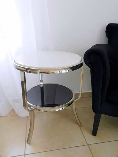 שולחן צד עשוי נירוסטה בשילוב שיש לבן בחלק העליון ופלטה זכוכית שחורה.